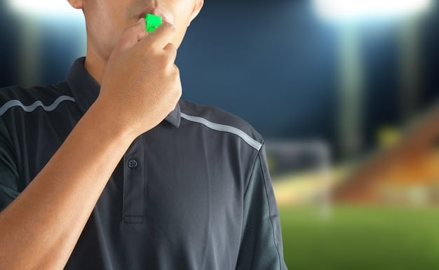 A close-up of a referee's whistle and stopwatch, symbolizing the precise timing and rule enforcement required during a football match.