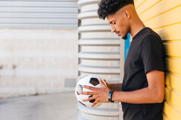 A young male soccer player intently listening to a coach on a training pitch, symbolizing player development and strategy.
