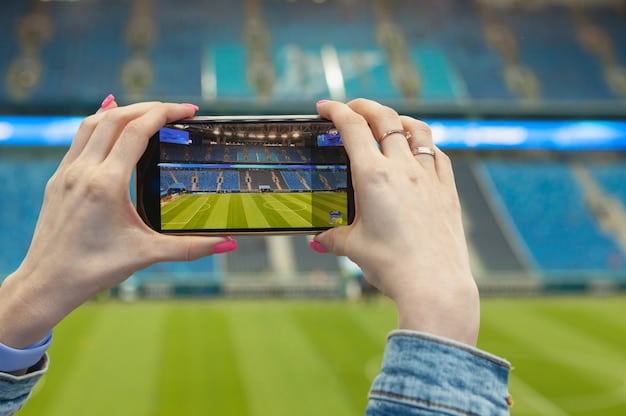 A close-up shot of a smartphone screen displaying a live football match stream, with vibrant colors and clear imagery, set against a blurred background of a living room with general sports memorabilia.