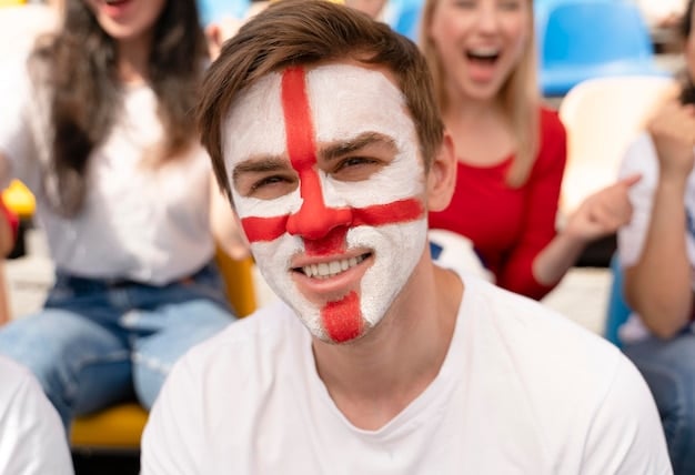 A close-up shot of a football fan painting their face with their national flag colors, surrounded by other cheering fans in the stadium.