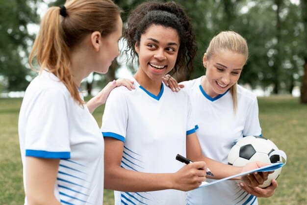 A group of young girls participating in a soccer clinic, with FIFA coaches providing instruction and encouragement. The setting is a sunny outdoor field, and the girls are wearing soccer uniforms. The image showcases FIFA's commitment to grassroots development in line with FIFA's Strategies for Growing Women's Soccer: A Focus on the US Market.