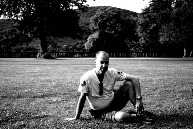 A candid, black and white photo of a football player sitting alone on the bench, head in hands, deep after a tough loss. The image shows the raw emotion and personal struggle athletes face behind the scenes. The lighting and composition highlight his isolation, emphasizing the contrast between public glory and private disappointment for Behind the Scenes: Exclusive Interviews with Players and Coaches – Get the Inside Scoop