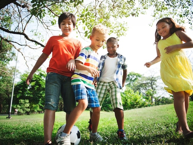A diverse group of children playing soccer in a neighborhood park, wearing different jerseys and laughing. The image showcases the widespread participation in youth soccer and the potential for the 2026 World Cup to further boost its popularity, contributing to the World Cup Legacy: How the 2026 Tournament Could Shape the Future of Soccer in the US.