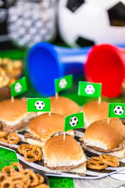 A close-up shot of various food and beverage stalls within a World Cup fan zone. The stalls are brightly decorated with national flags and team colors, and vendors are shown serving customers with enthusiasm. The shot captures the diverse culinary offerings and the bustling atmosphere of World Cup Fan Zones: Where Will the Biggest Public Viewing Parties Be Held Across the US in 2026?.