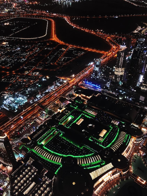 A drone shot of a modern US soccer stadium at night, showcasing its advanced lighting system, large video screens displaying live game action, and connected fan experience through visible Wi-Fi hotspots, demonstrating What are the Latest Innovations in US Soccer Stadium Technology for Fan Engagement.