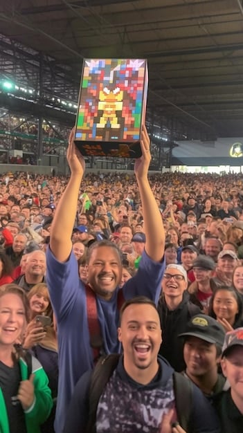 Fans in a stadium cheering and holding up their smartphones, displaying a team's fan reward app that is powered by blockchain technology. The app shows reward points, exclusive content, and team information. Mention How are US Soccer Clubs Using Blockchain for Secure Ticket Sales and Fan Rewards? in the description.