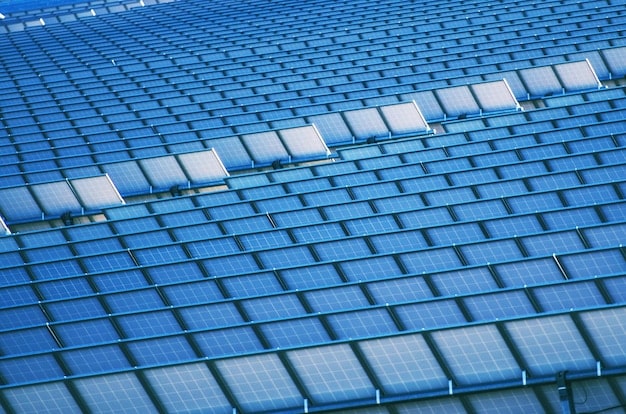 A close-up shot of solar panels installed on the roof of a soccer stadium in the US. The panels are gleaming in the sunlight, and the background shows the stadium seating and the green playing field. The image showcases the use of renewable energy technology to promote sustainability in a soccer stadium.